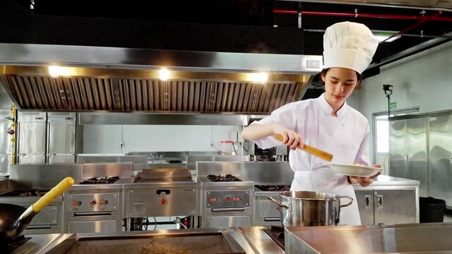 Young culinary student in a white chef uniform plating hot pasta from a steaming pot in a professional kitchen, demonstrating practical cooking skills during chef training at a culinary institute.