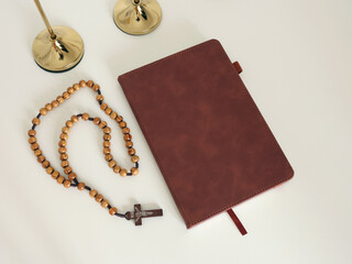 Catholic corner at home. Wooden rosary beads, cross, and prayer book. Faith, symbols, and traditions.