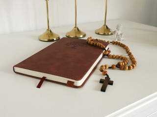 Catholic corner at home. Wooden rosary beads, cross, and prayer book. Faith, symbols, and traditions.