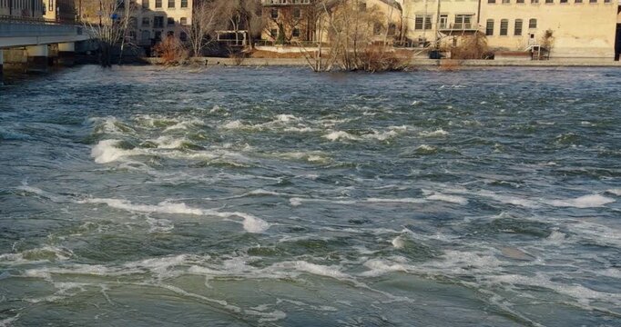 Slow Panning Shot of Rapid River Currents Flowing Down the Fox River with old historic paper Mills in background, Appleton, Wisconsin Daytime