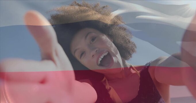 Animation of russian flag waving over woman talking selfie video through camera at beach