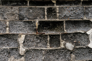 Close-up of an old cracked wall with exposed hole and rough stone surface, showing wear, erosion, and urban deterioration in detail