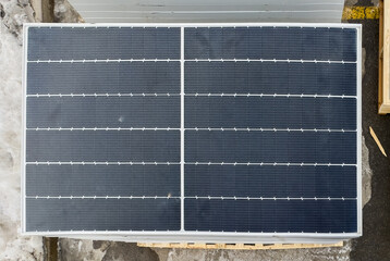 Top down view of a stack of photovoltaic solar panels on a wooden pallet at a construction site in winter.