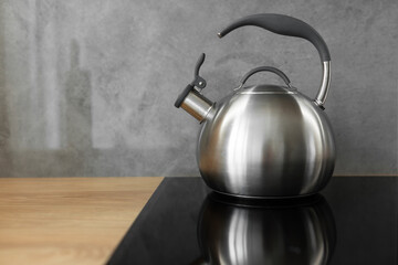 Photo of gray stainless steel kettle on the induction cooktop in the kitchen.