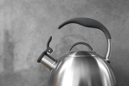 Photo of gray stainless steel kettle on the induction cooktop in the kitchen.