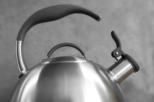 Photo of gray stainless steel kettle on the induction cooktop in the kitchen.