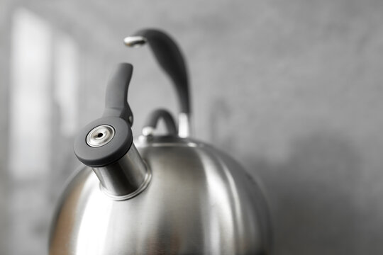 Photo of gray stainless steel kettle on the induction cooktop in the kitchen.