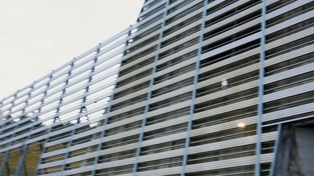 High noise barrier stands outside city near concert hall. Special construction provides sound absorption and comfortable environment