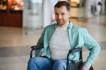 Portrait of smiling man sitting in wheelchair moving in shopping mall