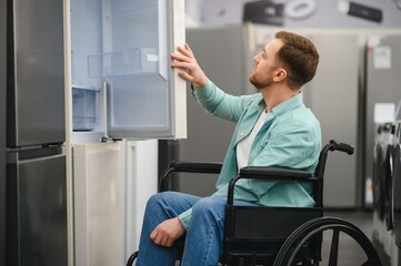 Customer in wheelchair choosing refrigerator in home appliance store