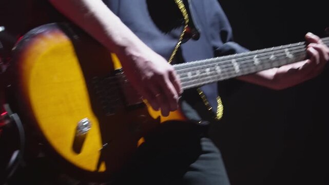 Talented guitarist plays rock music on stage in night club closeup. Man musician performs electric instrument solo at festival concert