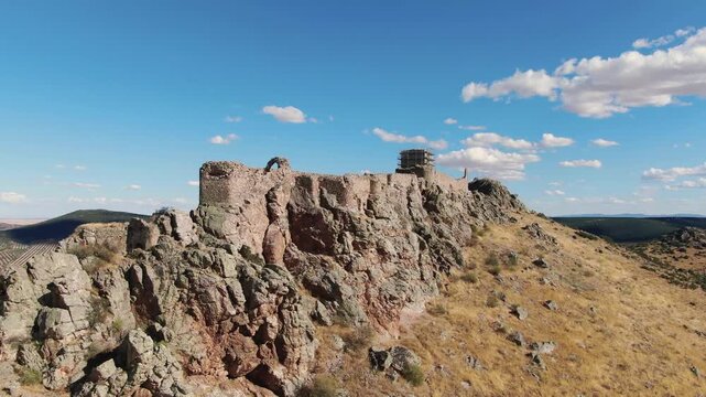 Orbital drone flight reveals the elongated layout of Pe&ntilde;as Negras Castle built along a rocky ridge, showing how the fortress adapts to the narrow hilltop landscape.
