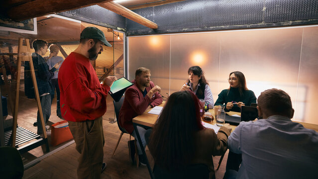 Diverse team discussing ideas during modern office meeting. Concept of collaborative workflow, confident teamwork, business communication for corporate and startup projects.