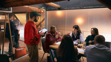 Creative professionals brainstorming together in modern office interior. Concept of innovative thinking, energetic teamwork, startup culture for business presentations and media.