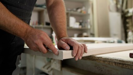 Close up of a skilled carpenter meticulously sanding the edge of a wooden plank. Professional...