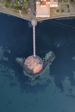 Aerial view of the vibrant Casina Vanvitelliana standing boldly in the dark waters of Fusaro Lake, connected by a long pier, Bacoli, Campania, Italy.