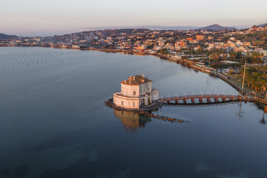 Aerial view of the iconic Casina Vanvitelliana standing gracefully in the tranquil Fusaro Lake, its reflection shimmering on the water's surface, Bacoli, Campania, Italy.