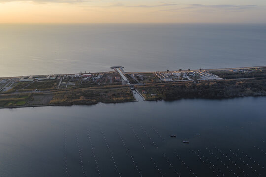 Aerial view of the serene Fusaro Lake meeting the Tyrrhenian Sea with a long strip of land and buildings, Fusaro Lake, Bacoli, Campania, Italy.