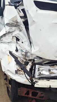 Front-end collision damage on van: smashed headlight, bumper, grille, and hood after road accident