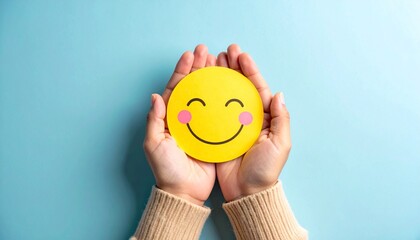 Hands cupping yellow smiley face with closed eyes and pink cheeks on light blue background