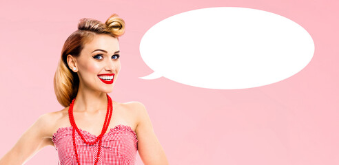 Portrait image - happy smiling blond hair woman in red dress. Cute pin up pinup girl. Retro vintage ad concept. Isolated rose pink background with white empty mockup speech bubble with free text space
