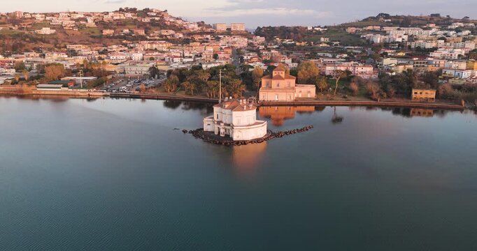 Aerial view of the Casina Vanvitelliana standing prominently on the lake with the city as a backdrop, Fusaro Lake, Campania, Italy.