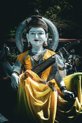 Fototapeta premium Beautiful view of a statue of the Hindu deity Saraswati playing veena on the shore of the sacred lake Ganga Talao, Grand Bassin, Mauritius