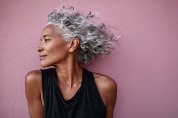 tender afro-american woman in her 50s showing off a lightweight base layer on solid pastel color wall