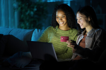Happy diverse women buying online in the night at home