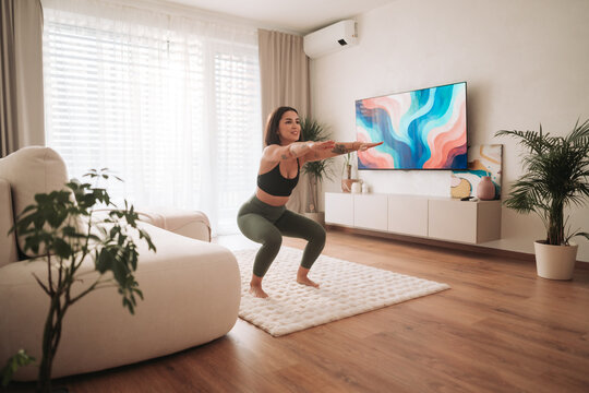 modern living space with fitness activity, woman performing squat amid stylish home decor and natural light