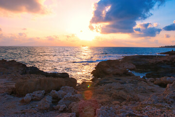 Obraz premium 04 June 2023: Beautiful sunset view of breaking waves at Petra tou Romiou beach, in Paphos, Cyprus. It is considered to be Aphrodite's birthplace in Greek mythology.