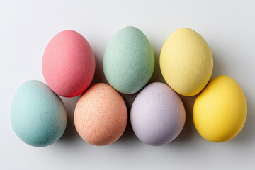 Flat lay of pastel colored Easter eggs arranged on a plain surface with various shades and textures
