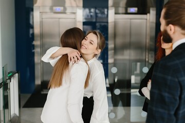 Businesswomen hugging in modern corporate office building