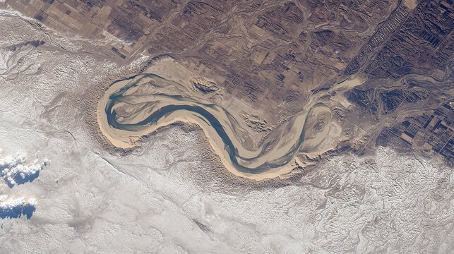A stunning aerial view from space of a massive, sinuous sand dune resembling a slug, dramatically cutting through a textured floodplain landscape.