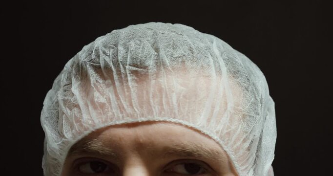 Close-up of a person already wearing a disposable medical hair net, slowly turning their head. Concept of hygiene compliance, safety standards, and professional cleanliness in medical, laboratory, foo