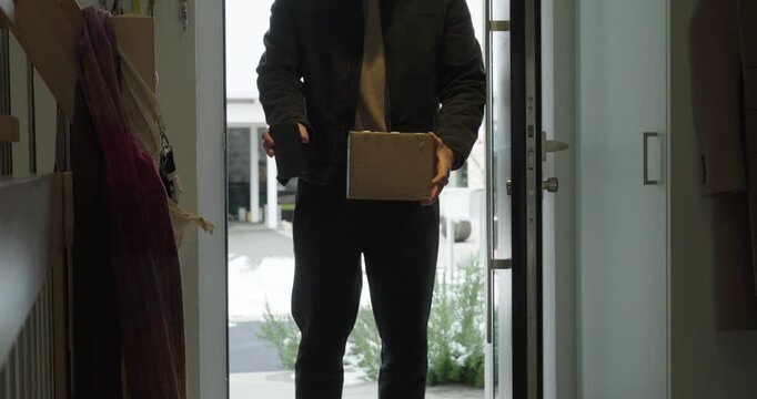 A delivery person hands over a parcel while the recipient signs digitally on a smartphone. Concept of contactless delivery, proof of delivery, modern logistics, and e-commerce convenience.