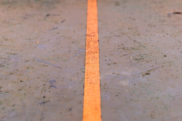Striking contrast of an orange line on a weathered gray surface in an industrial setting creates a captivating perspective