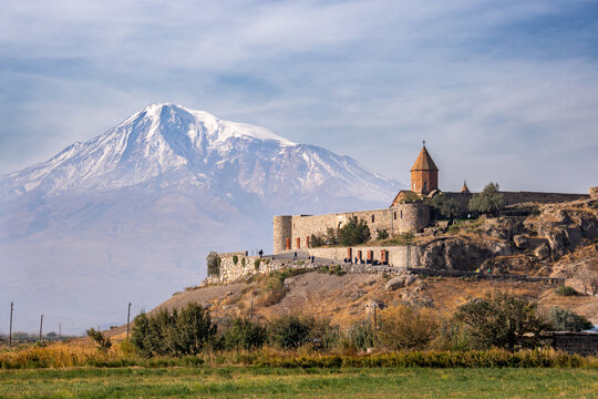 Scenic view of the historic Khor Virap Monastery against the snow-capped Mount Ararat in Armenia on a sunny day.