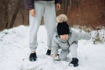 Toddler playing in fresh snow with mom