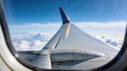 Airplane Wing View Above Clouds at Altitude Through Window