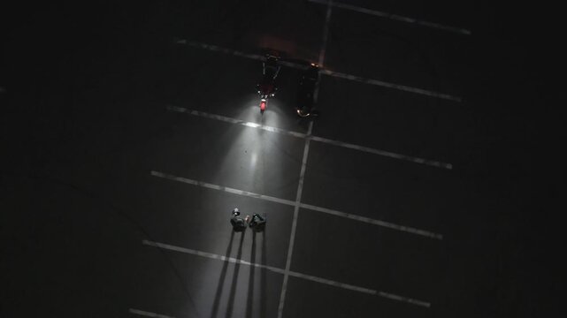 Drone view of two motorcycles parked in an open lot. Minimal urban scene showing symmetry, space, and quiet pause between rides from an aerial perspective. night view