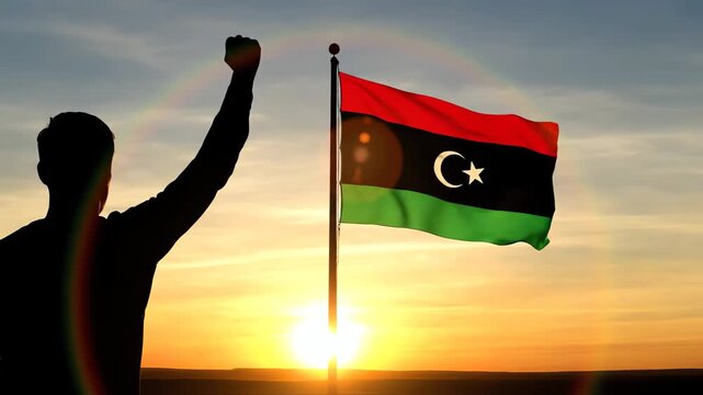 Man Celebrating with Raised Fist Near Libyan Flag at Sunset