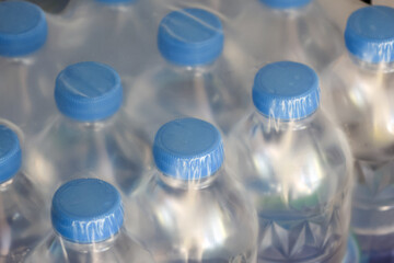 Pack of clear plastic water bottle with blue cap shrink wrapped reflecting fresh and clean hydration concept in supermarket shelf display representing pure mineral drink industry supply
