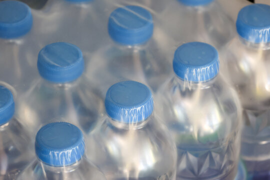 Pack of clear plastic water bottle with blue cap shrink wrapped reflecting fresh and clean hydration concept in supermarket shelf display representing pure mineral drink industry supply