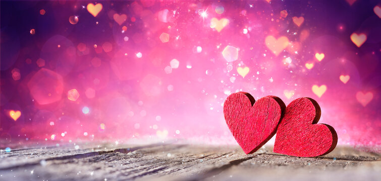 Valentines Day - Two Red Hearts On Wooden Table With Purple Glitter And Abstract Shiny Lights