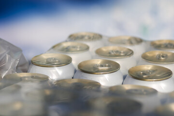 Close up view showing pack of aluminum beverage can wrapped in plastic film sitting outdoors waiting for recycling process to reduce environmental waste and pollution issues