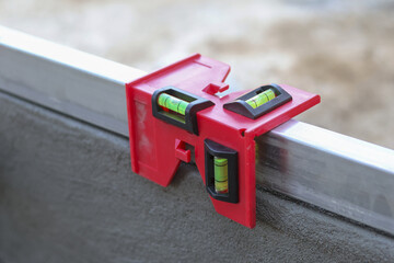 Red plastic post level clamped onto metal stud beam ensuring structure accurate and vertical alignment construction site showing reliable and focused attitude towards professional building