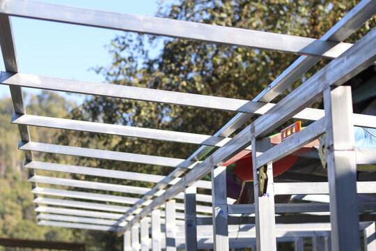 Unfinished metal roof structure frame against blue sky showing strong silver steel beam construction for industrial building project development