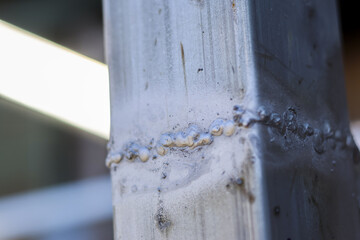 Detail close up vertical metal pipe with weld seam showing texture of sturdy steel joinery and industrial craftsmanship in construction site setting with strong feeling
