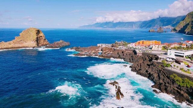 Aerial view of Porto Moniz seaside town bordered by rough Atlantic waters and steep coastal terrain on Madeira Island